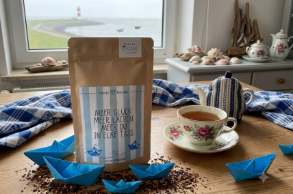Teepackung mit Tee-Tasse auf einem Tisch - Tisch dekoriert - Produkt "Meer Glück - Meer Lachen - Meer Du in Elke Tass"