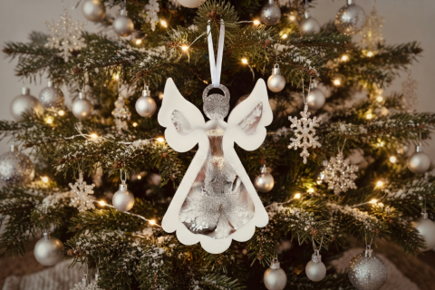 Engel aus Epoxidharz in weiß und silber mit weißem Satinband. Der Engel hängt an einem Tannenzweig eines Weihnachtsbaums. Der Baum ist ebenfalls in weiß und silber dekoriert