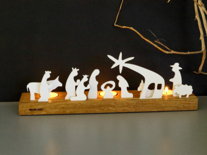 Krippenfiguren in zwei Nuten geführt in einem Eichesockel. dahinter drei leuchtende Teelichter