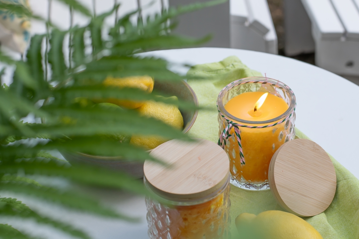 Citronella-Kerze steht auf dem Gartentisch mit Deko. 