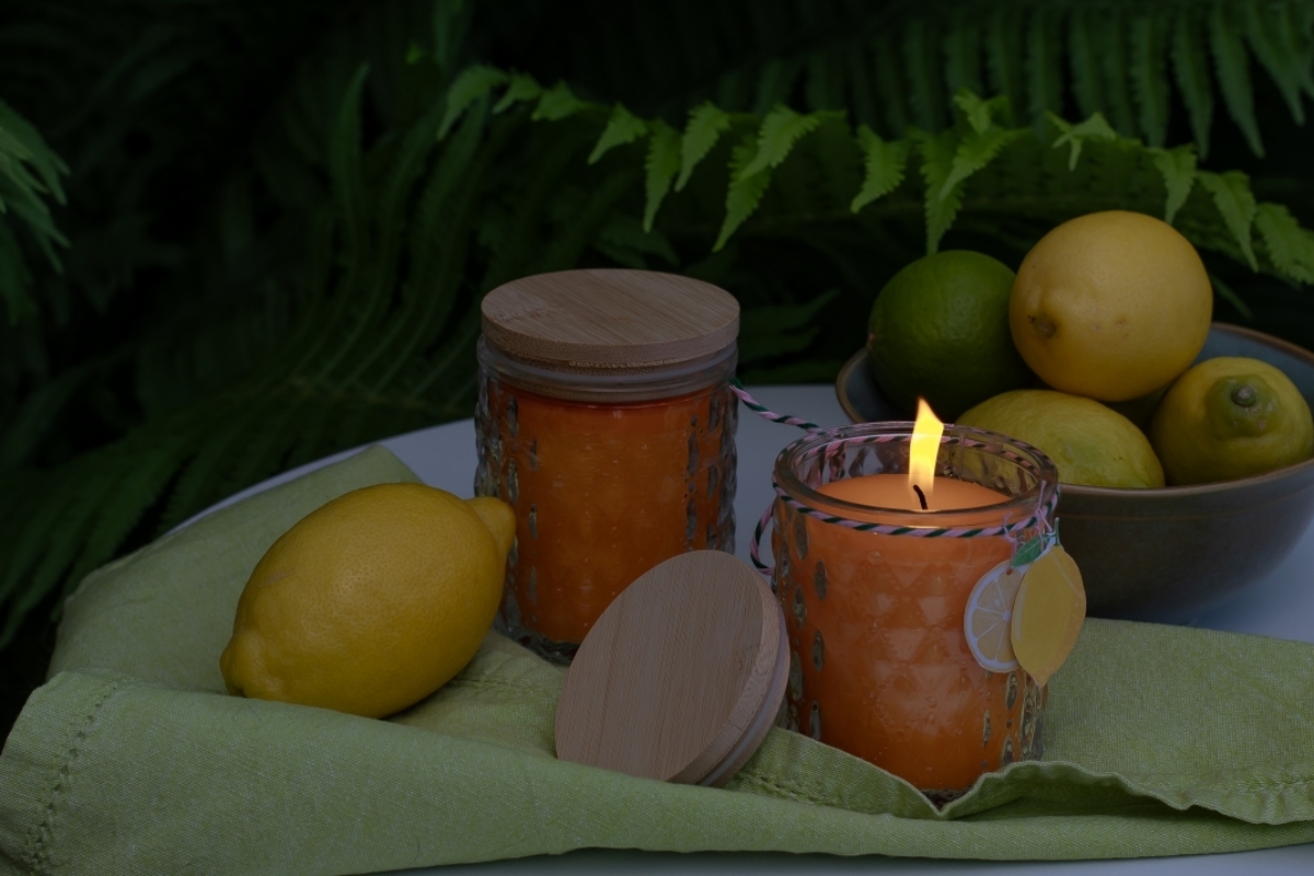 Citronella-Kerze steht auf dem Gartentisch mit Deko. 