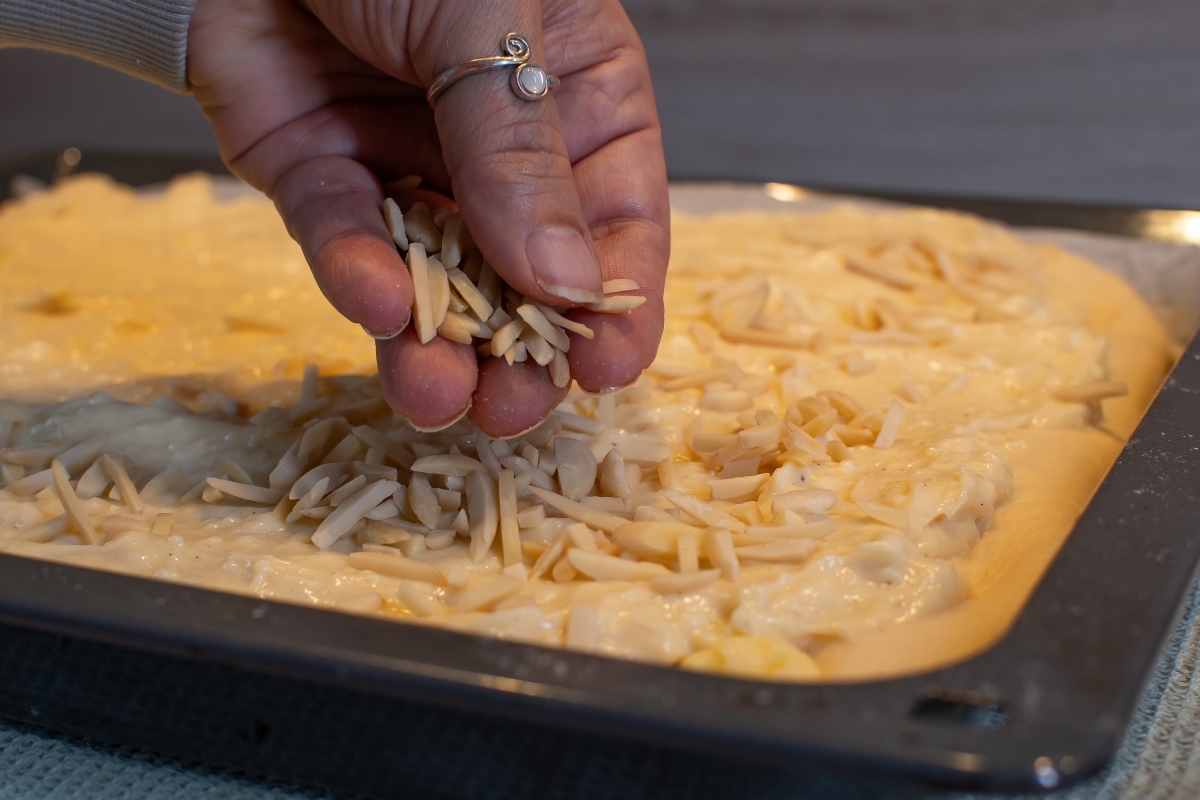 Mandelsplitter werden auf einem Kuchenteig verteilt.
