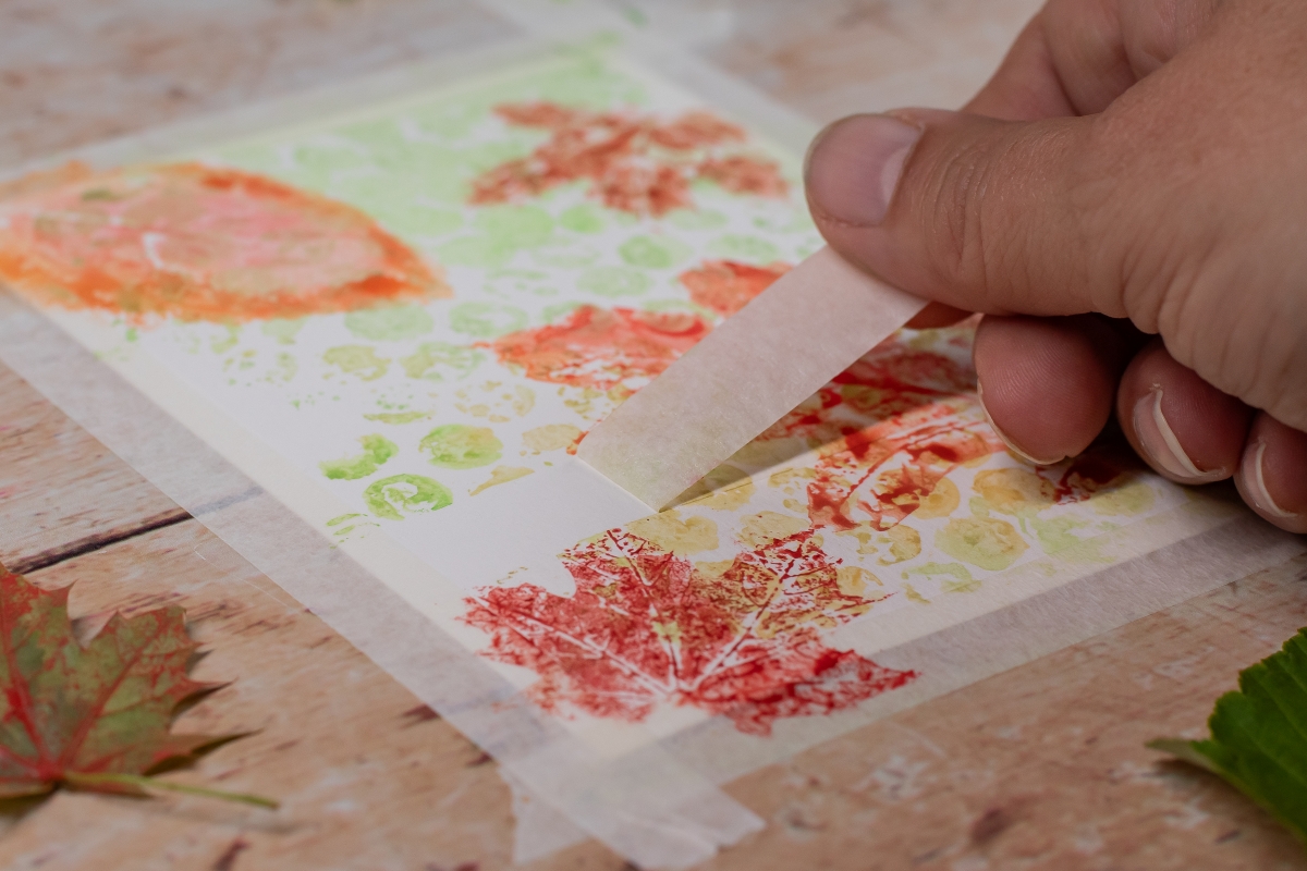 Ein Klebestreifen wird von einem Blatt Papier abgezogen.