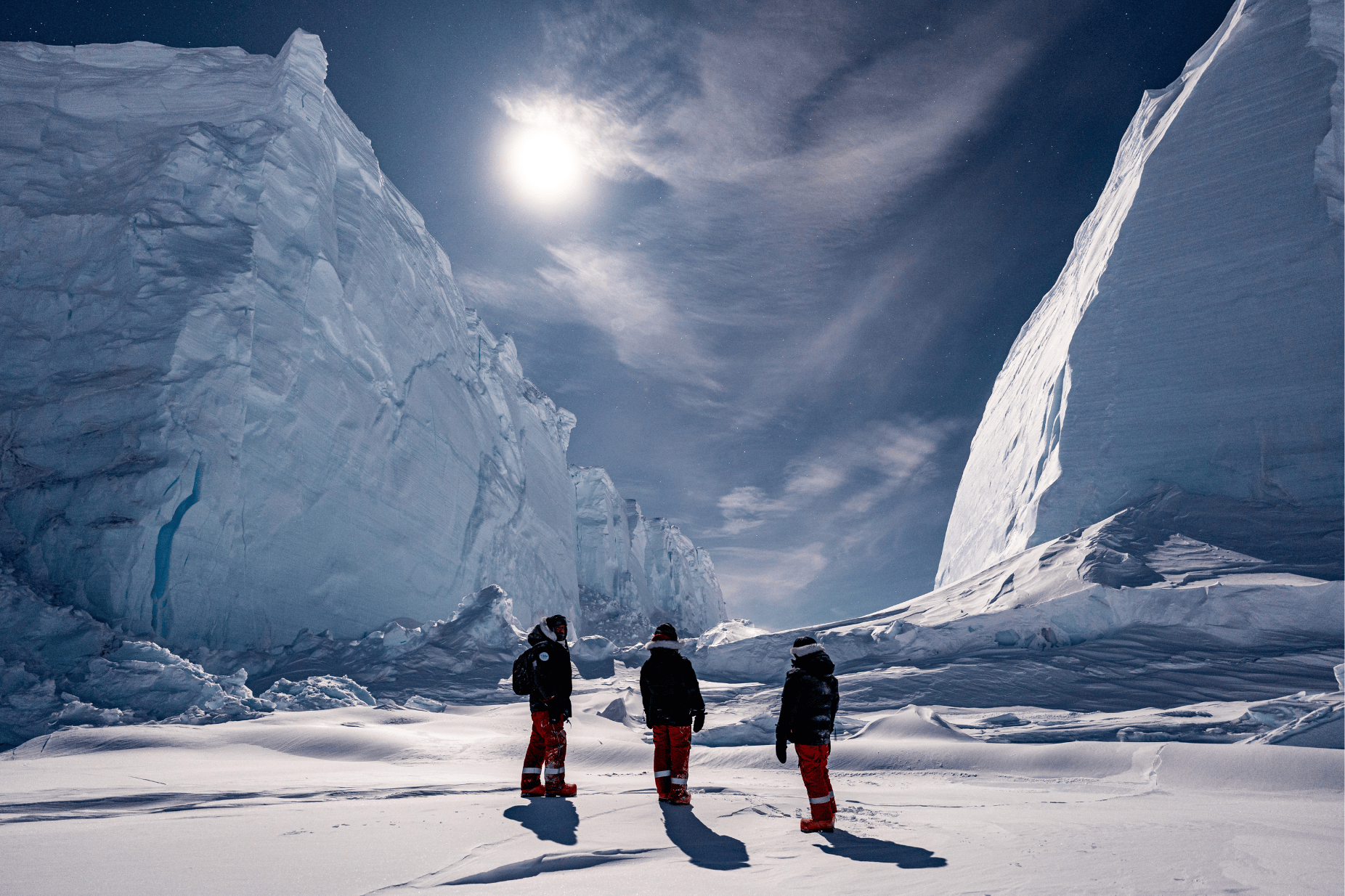 Drei Personen stehen vor einem Gletscher