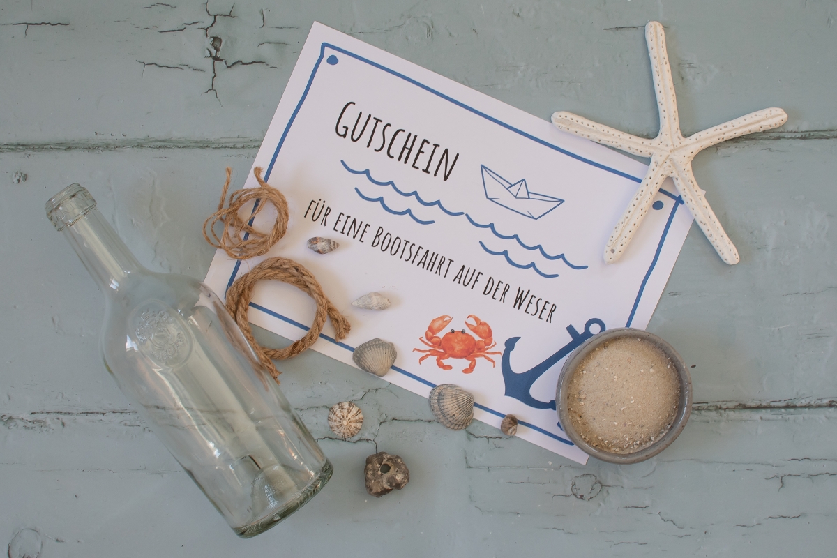 Bild von einem Gutschein inmitten von Muscheln und einer Flasche
